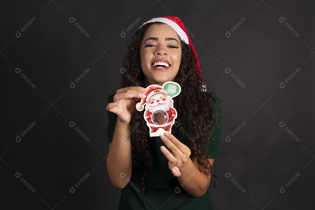 Mulher com gorro vermelho segurando lembrança de natal com brigadeiro