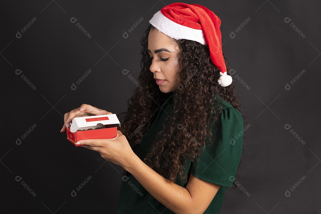 Mulher abrindo caixa de bombom e usando gorro vermelho