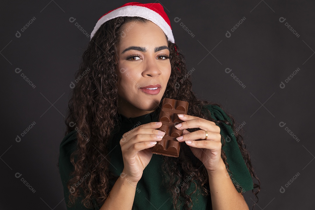 Uma linda mulher usando gorro e segurando barra de chocolate