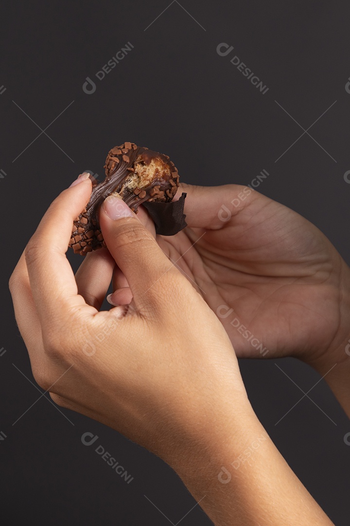 Mão segurando um delicioso brigadeiro de chocolate
