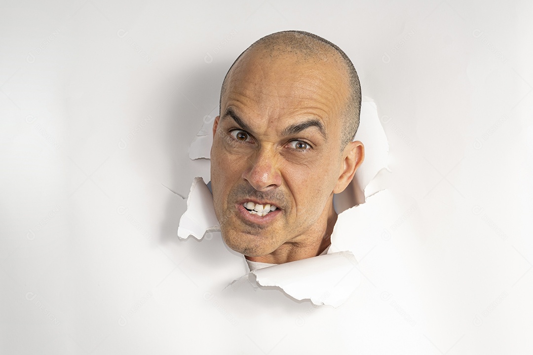 Homem com cabeça atráves de buraco no papel fazendo careta