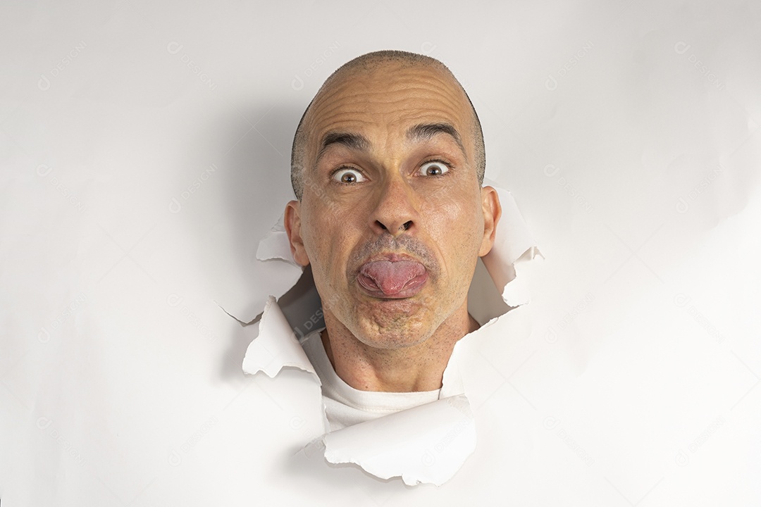 Homem fazendo caretas atráves de um buraco no papel