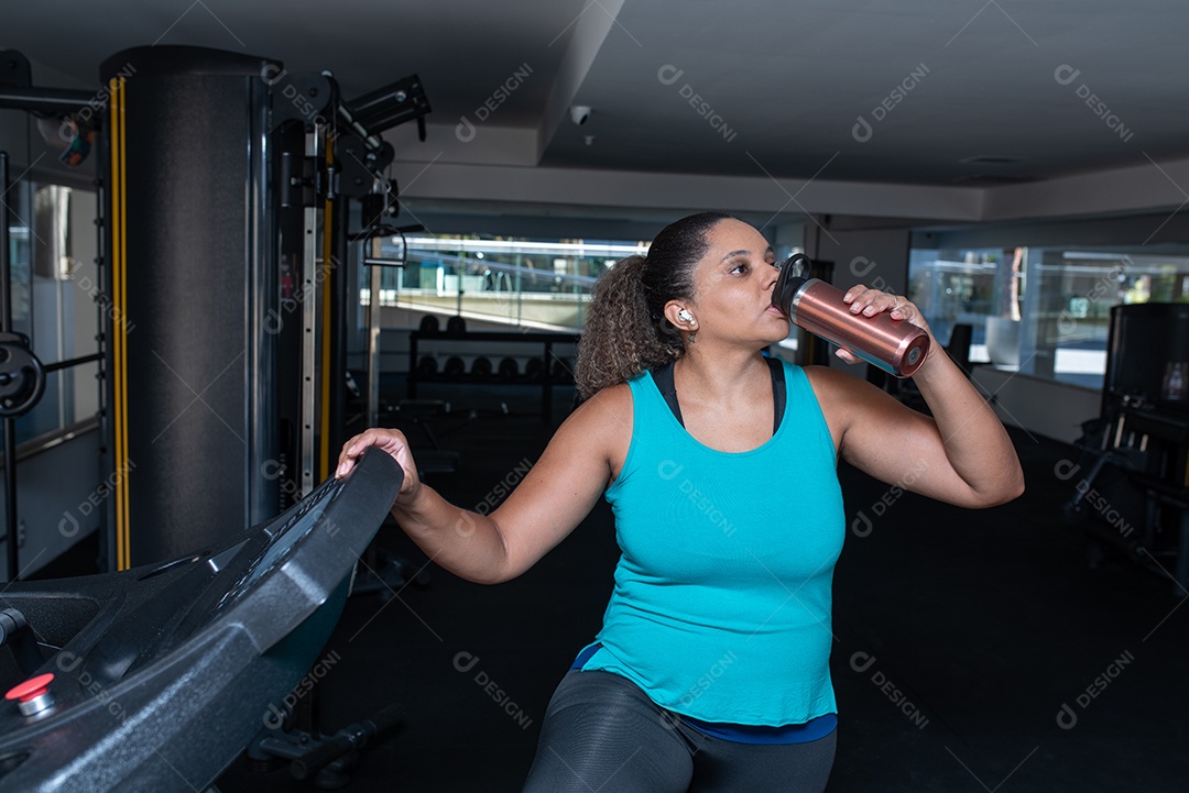 Mulher desportiva exercitando em multiestação na academia