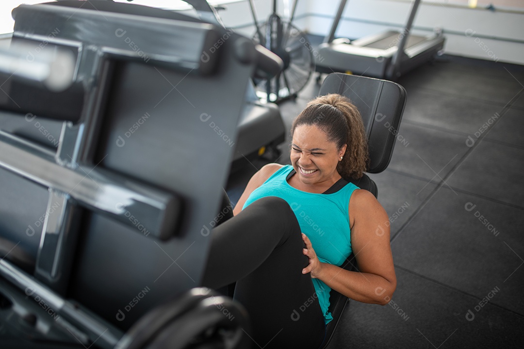 Mulher desportiva exercitando em multiestação na academia