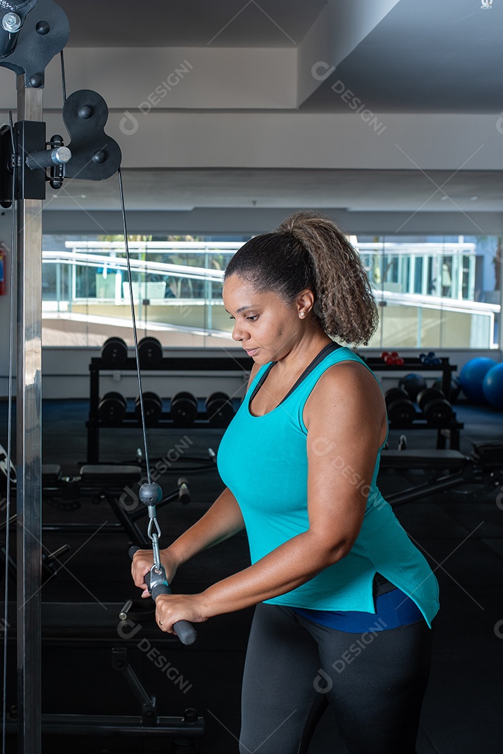 Mulher desportiva exercitando em multiestação na academia