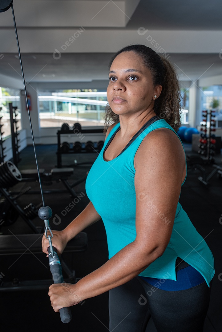 Mulher desportiva exercitando em multiestação na academia