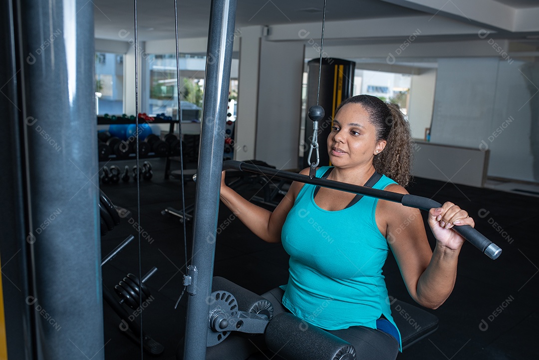Mulher desportiva exercitando em multiestação na academia