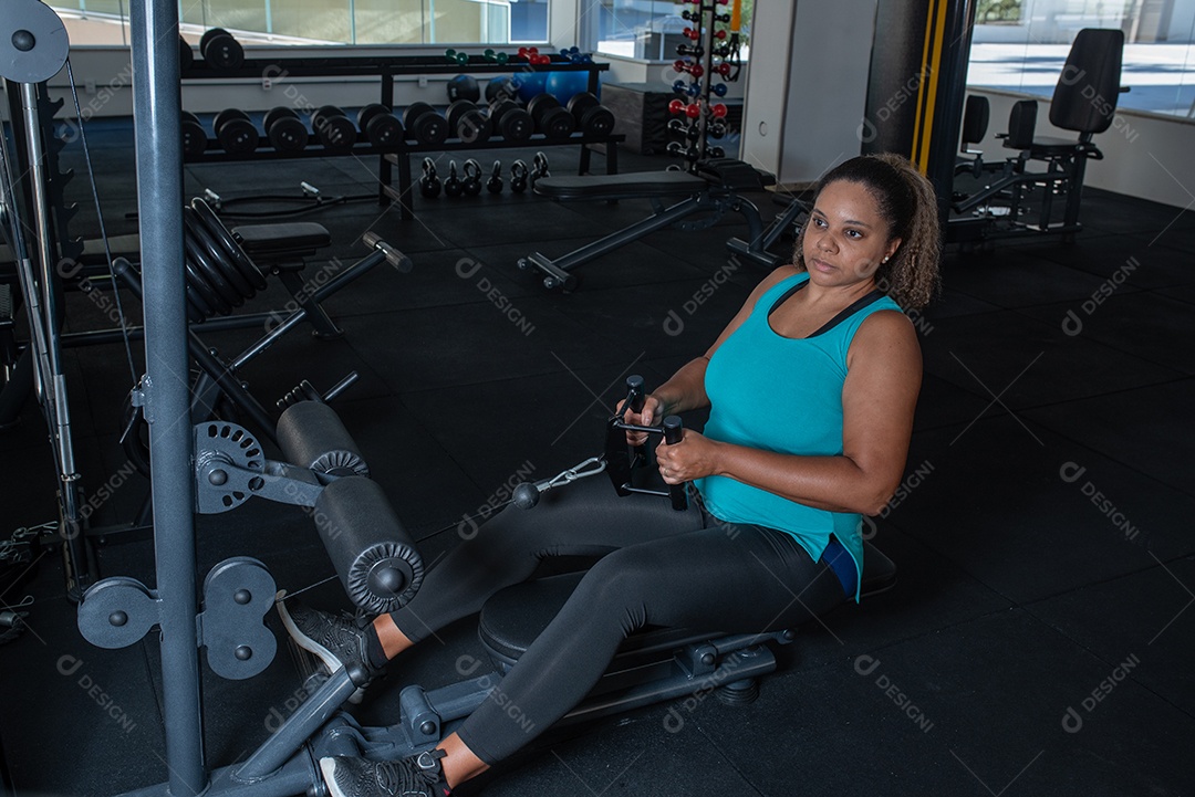 Mulher desportiva exercitando em multiestação na academia
