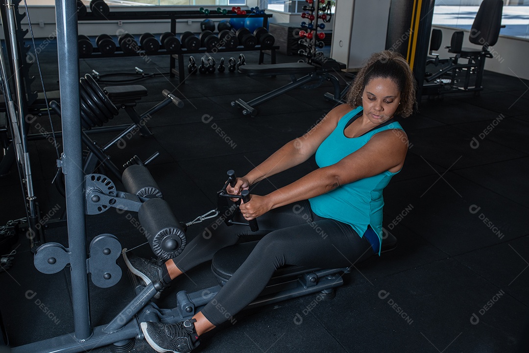 Mulher desportiva exercitando em multiestação na academia