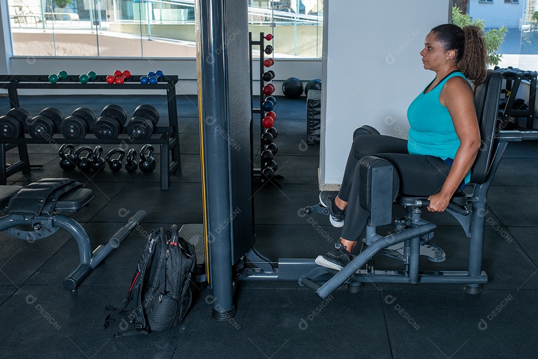 Mulher desportiva exercitando em multiestação na academia