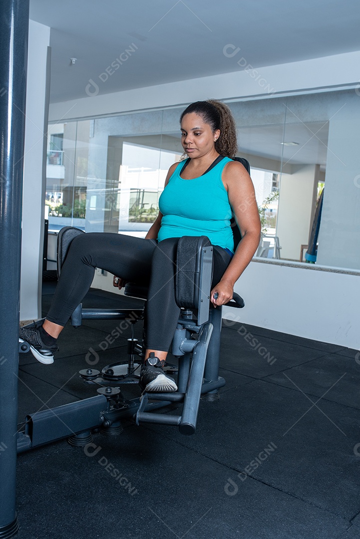 Mulher desportiva exercitando em multiestação na academia