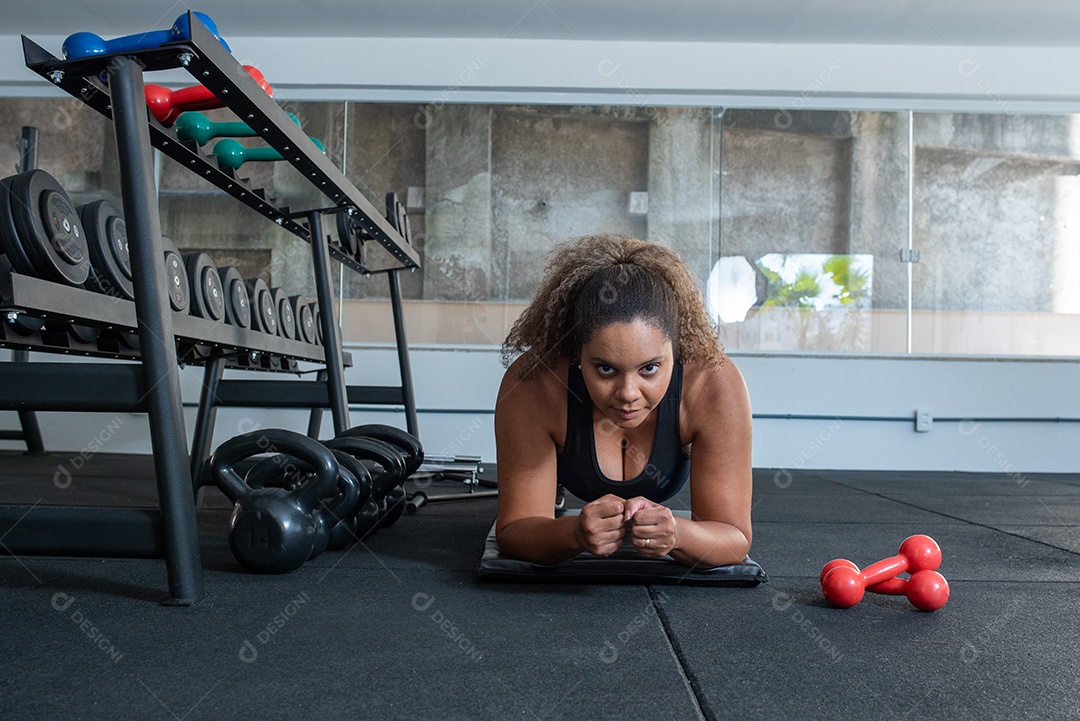 Mulher desportiva exercitando em multiestação na academia