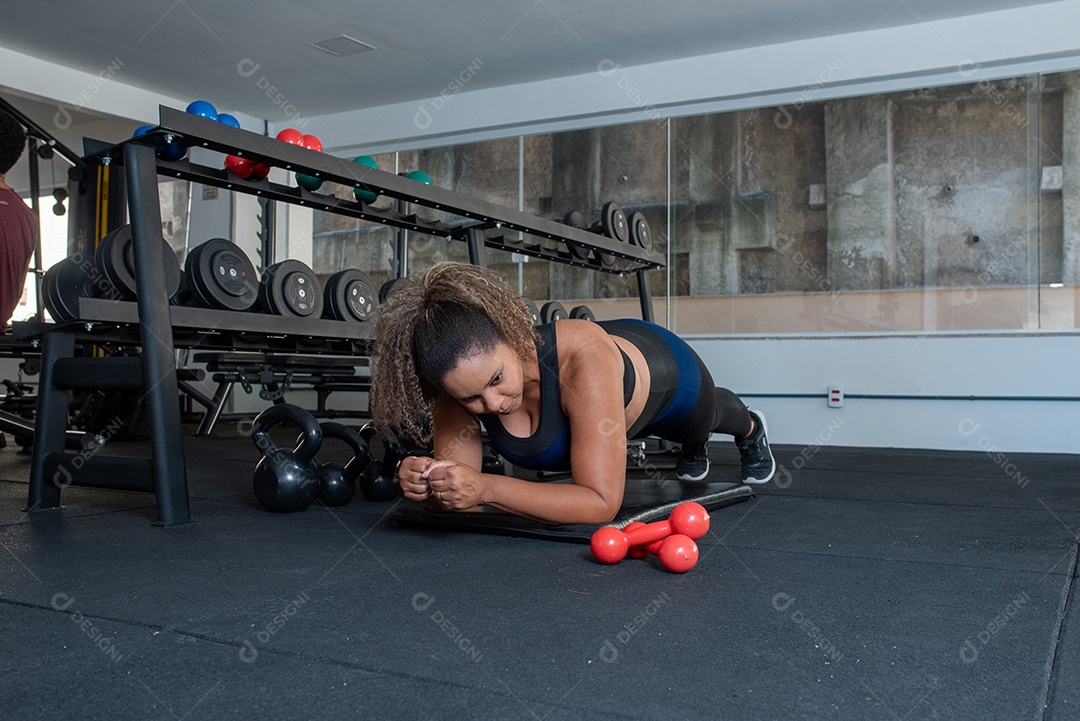 Mulher desportiva exercitando em multiestação na academia
