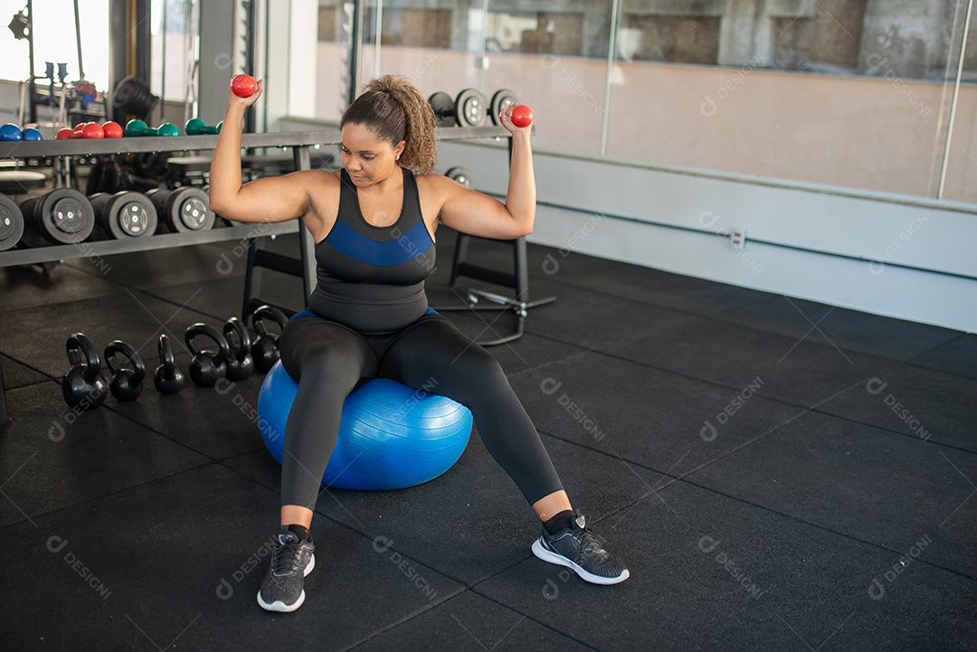 Mulher fazendo exercício com peso em cima da bola