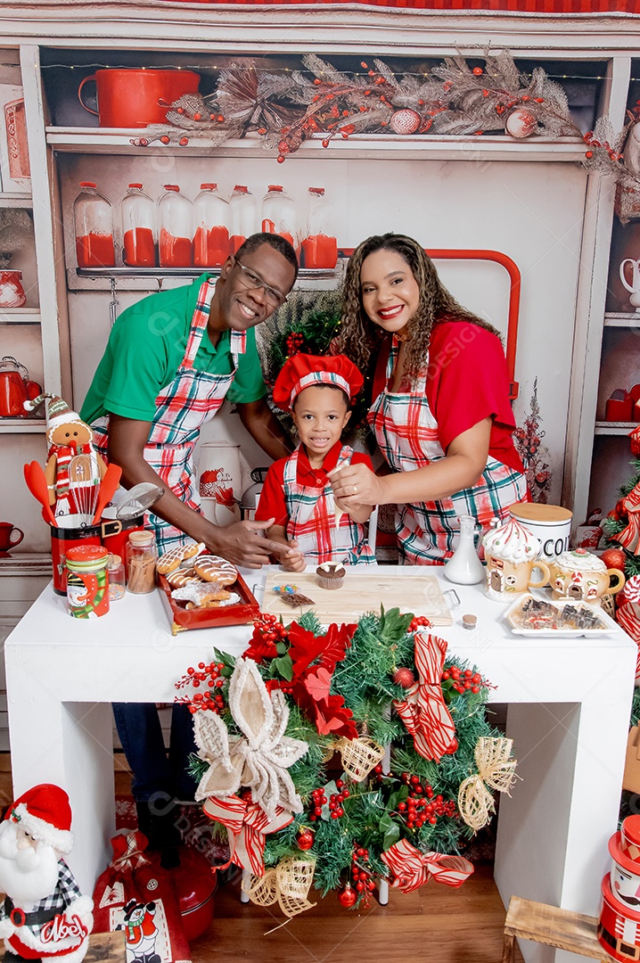 Uma linda família se divertindo na cozinha com bolos de natal