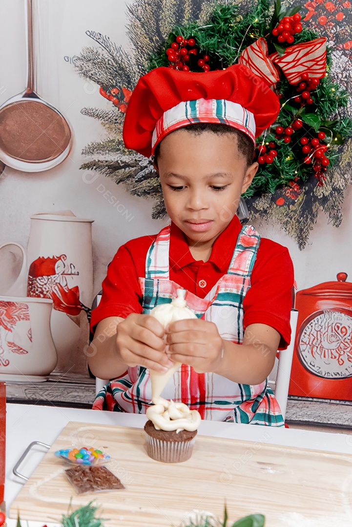 Um lindo menino com toque blanche e decorando um mini bolo