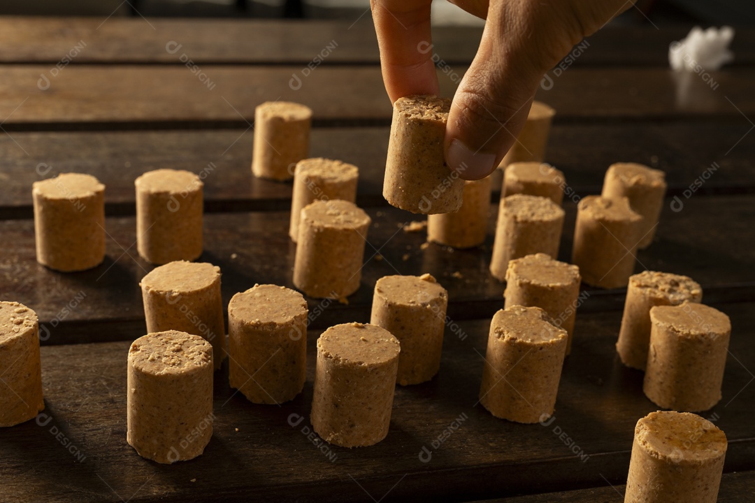 Mão pegando paçoca na mesa