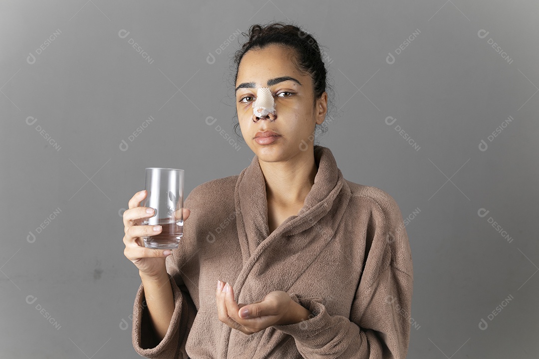 Mulher com mãos segurando remédios e copo dágua