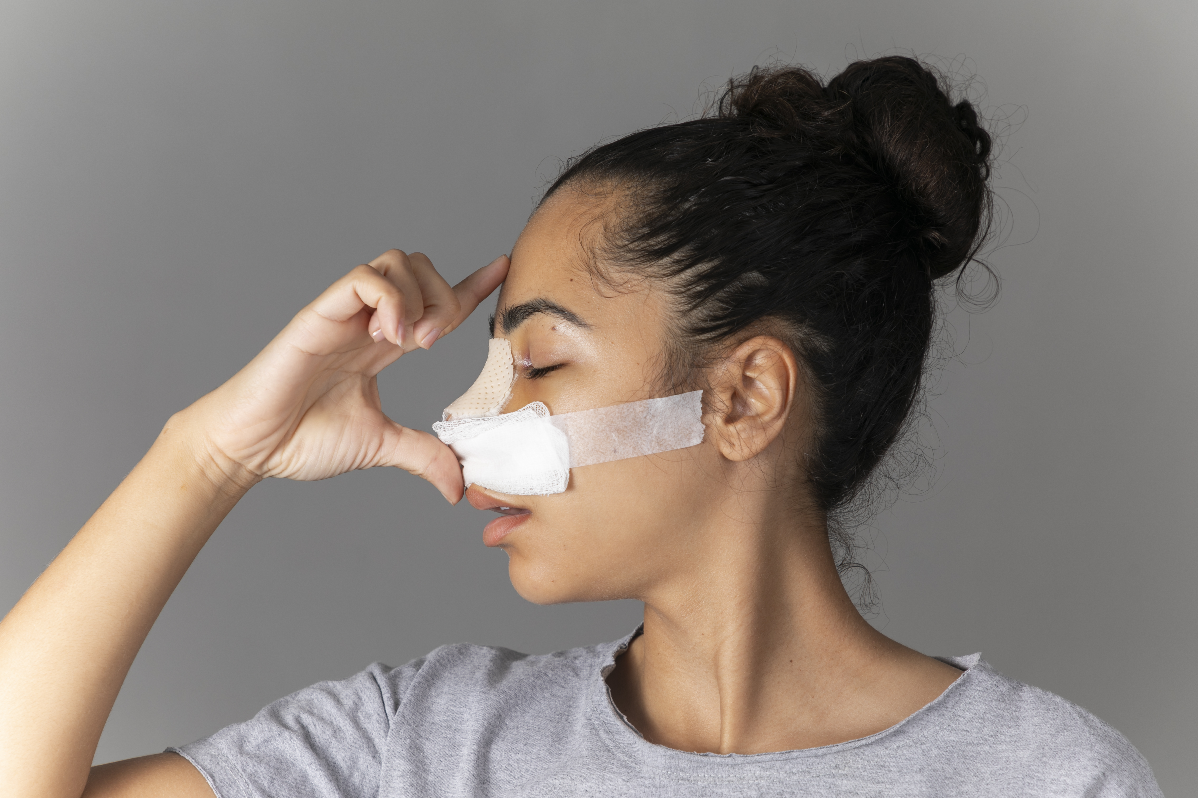 Mulher com cabeça para o lado e nariz com curativo