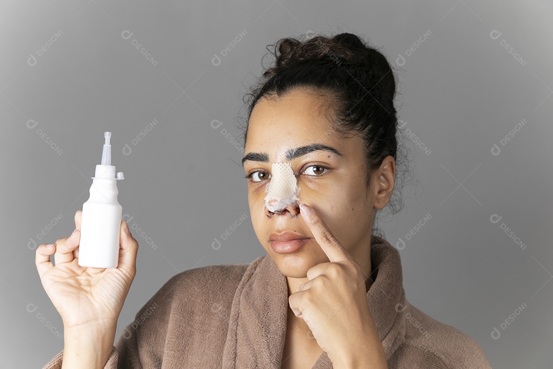 Mulher com remédio na mão e apontando para o nariz