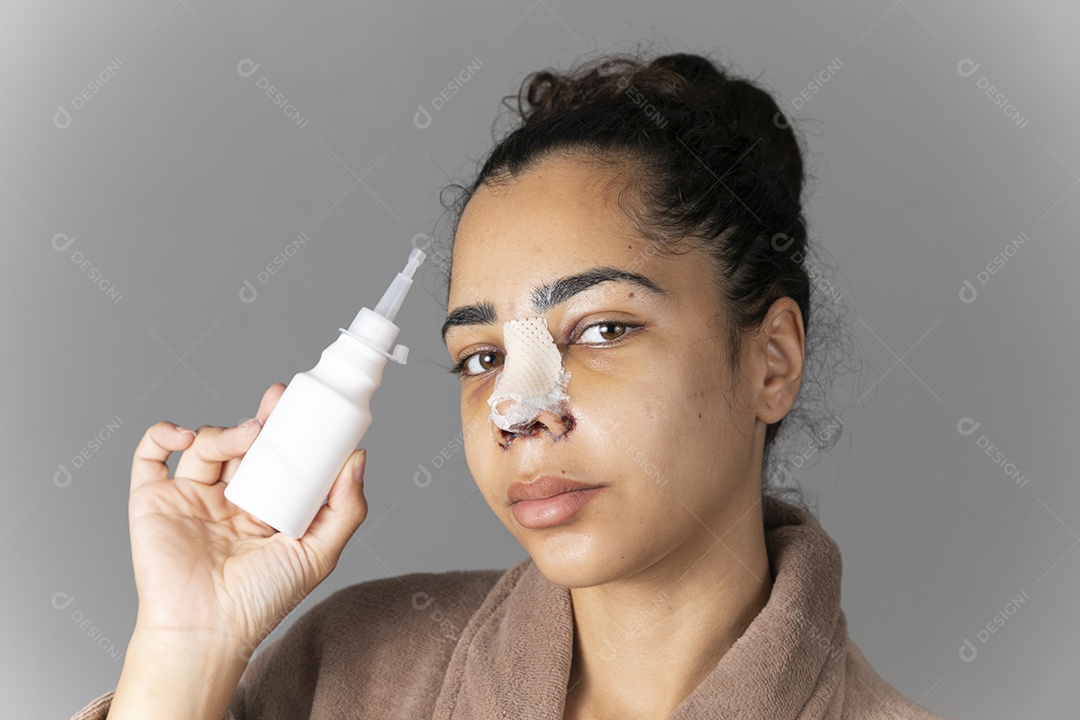 Mulher segurando vidro de remédio na mãos com nariz enfaixado