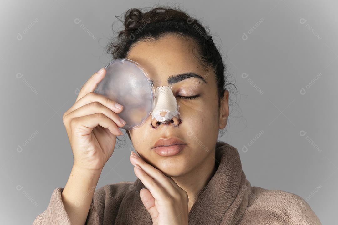 Jovem mulher com bolsa de gelo no rosto