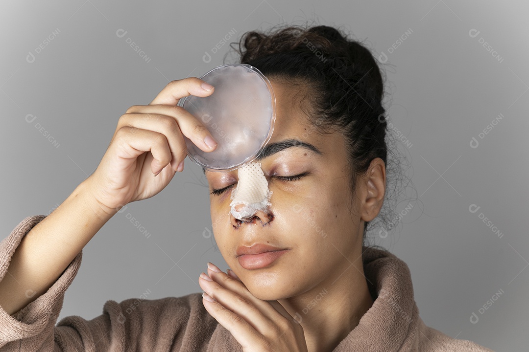 Jovem com gelo no rosto depois de uma cirurgia