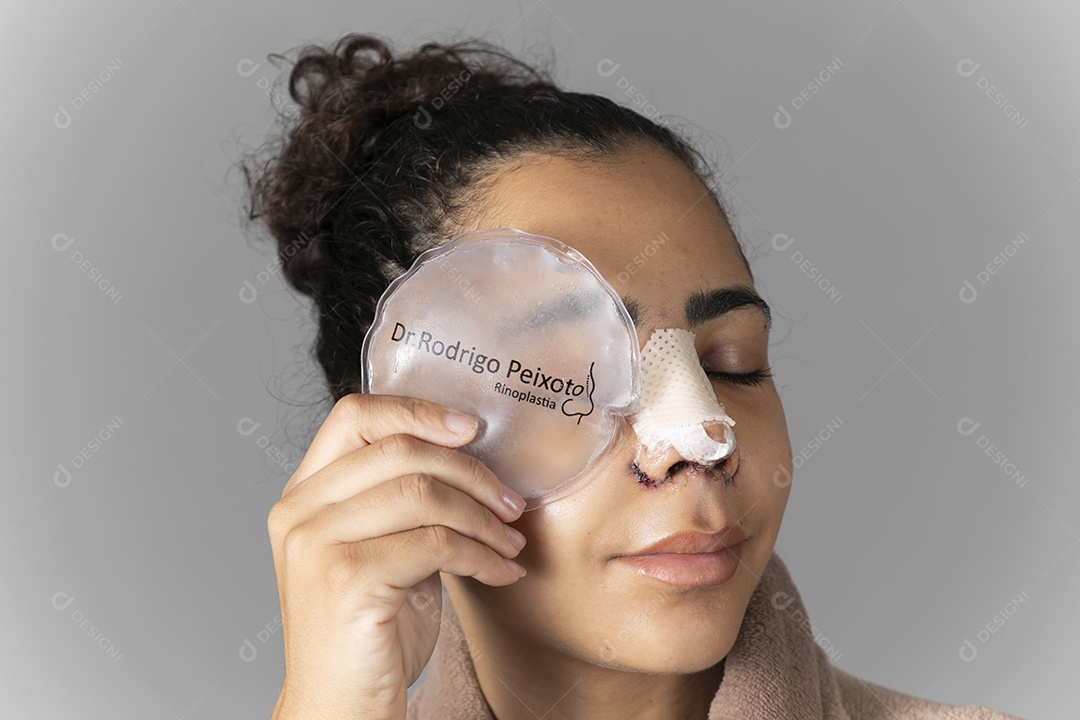 Jovem com bolsa de gelo no rosto depois de uma cirurgia