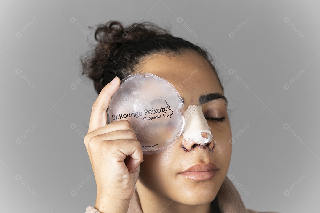 Mulher com bolsa de gelo no rosto depois de uma cirurgia