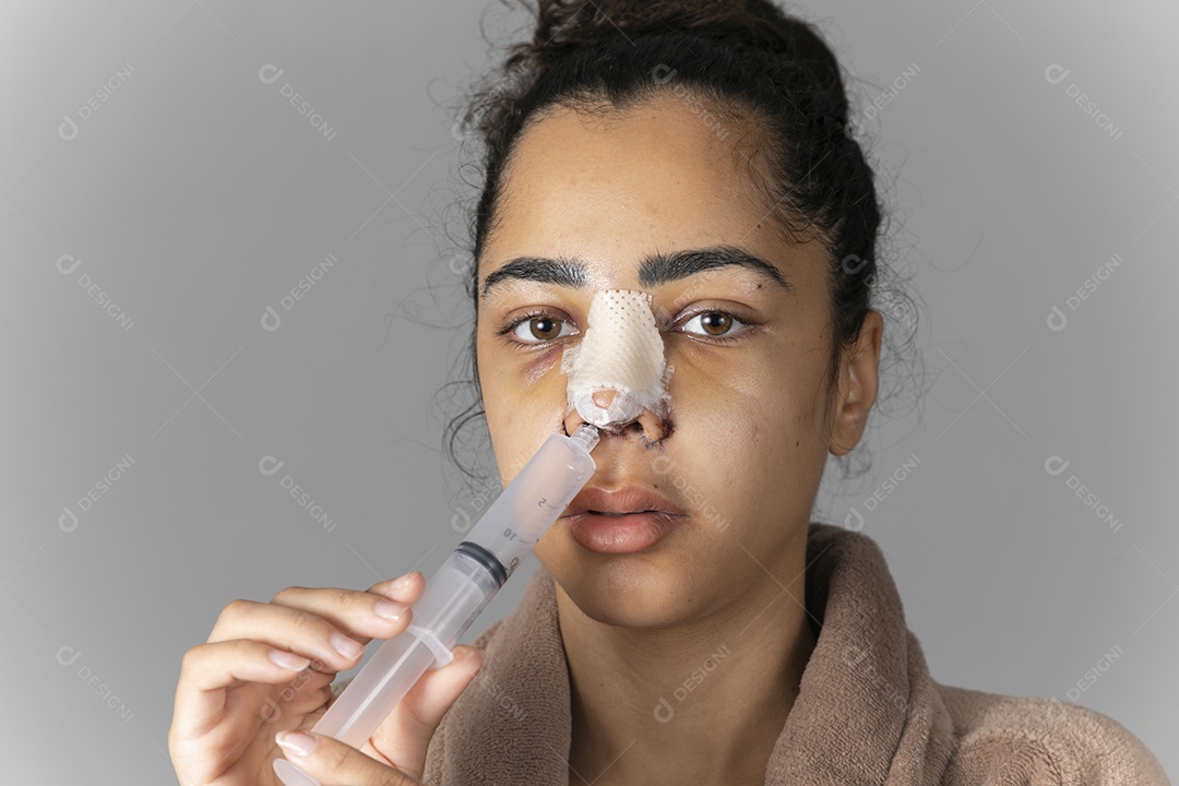 Jovem com seringa no nariz depois de uma cirurgia