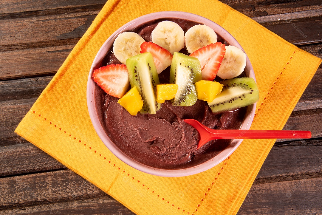 Tigela com delicioso creme de açaí com frutas sobre mesa de madeira