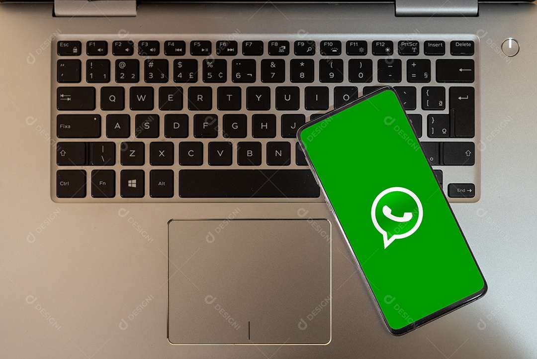 tela do celular com Whatsapp sobre teclado de um notebook