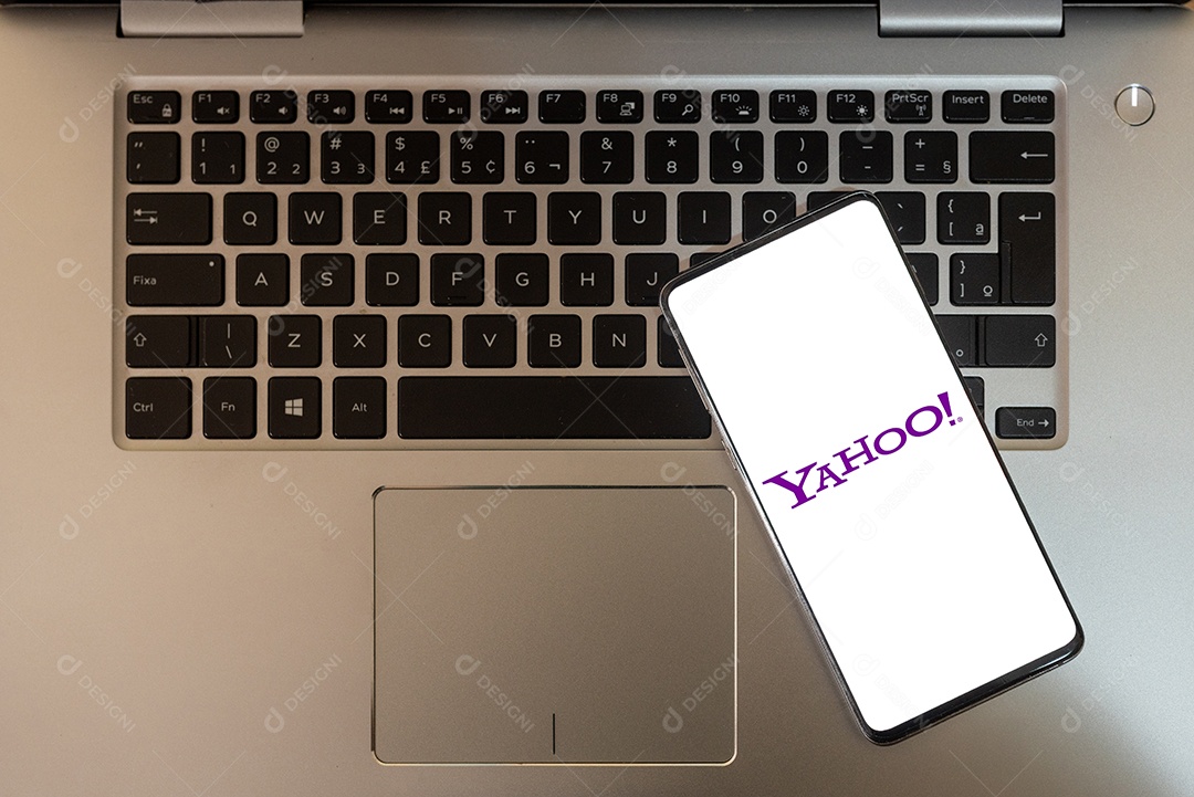 Tela de um celular com yahoo sobre teclado de notebook