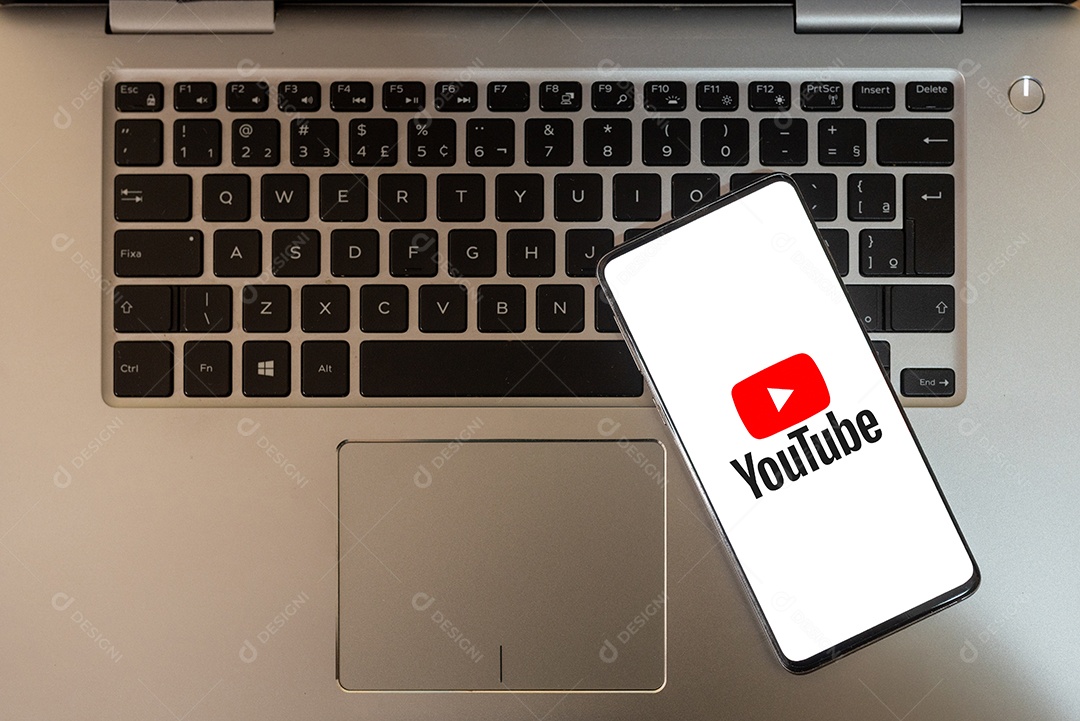 Tela de celular com youtube sobre teclado de um laptop