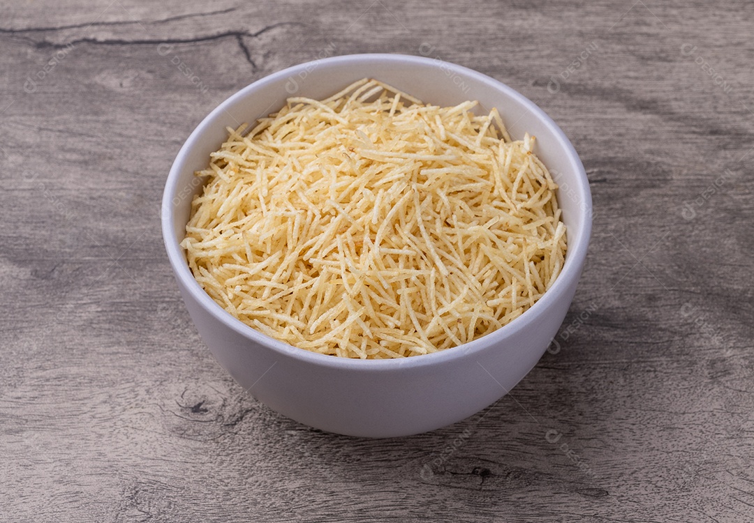 Batata palha em uma tigela sobre a mesa de madeira