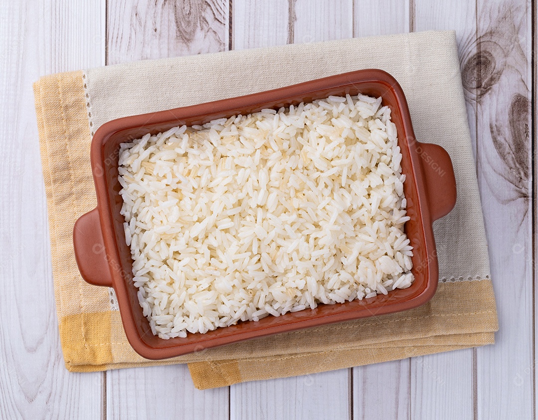 Arroz branco cozido em um prato sobre a mesa de madeira