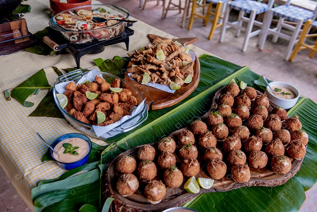 Bolinhos de peixe e filé de peixe frito em uma placa de madeira e folha de bananeira