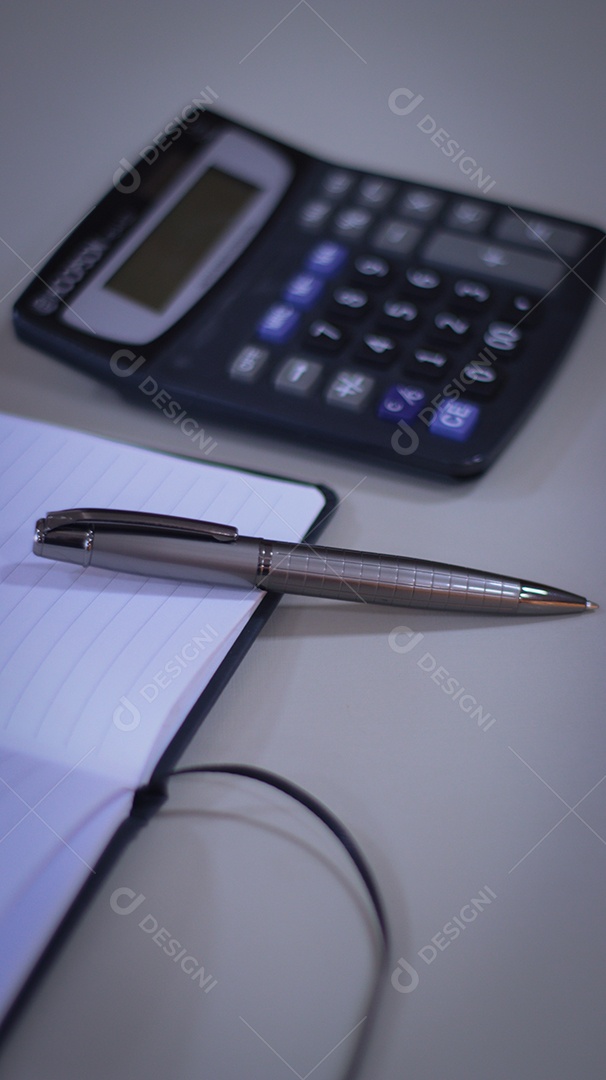 Caneca ao lado de uma calculadora sobre uma mesa de escritorio