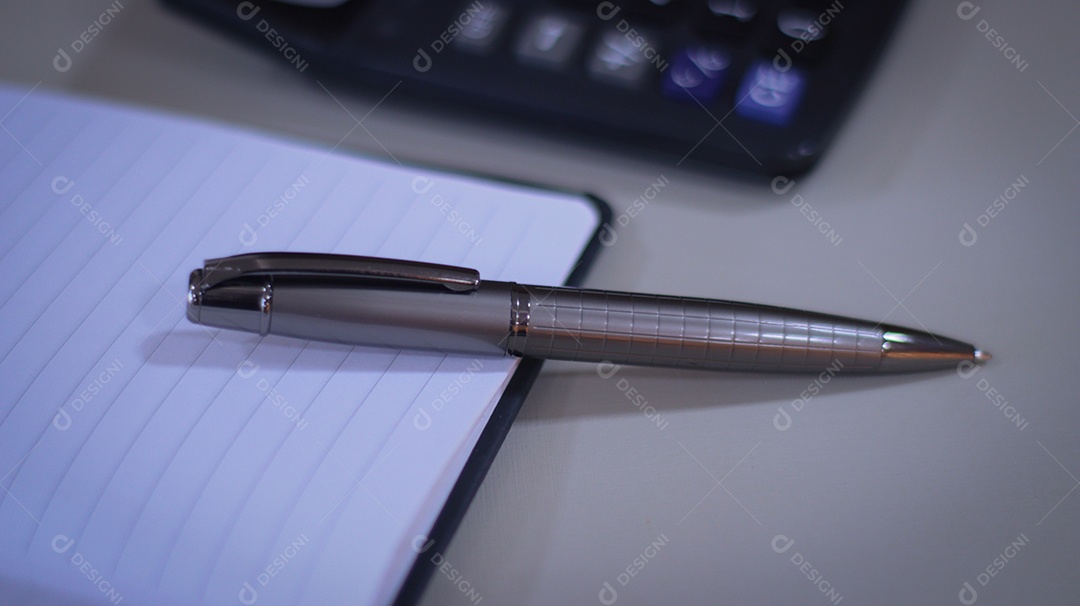 Caneta ao lado de uma calculadora sobre uma mesa de escritorio