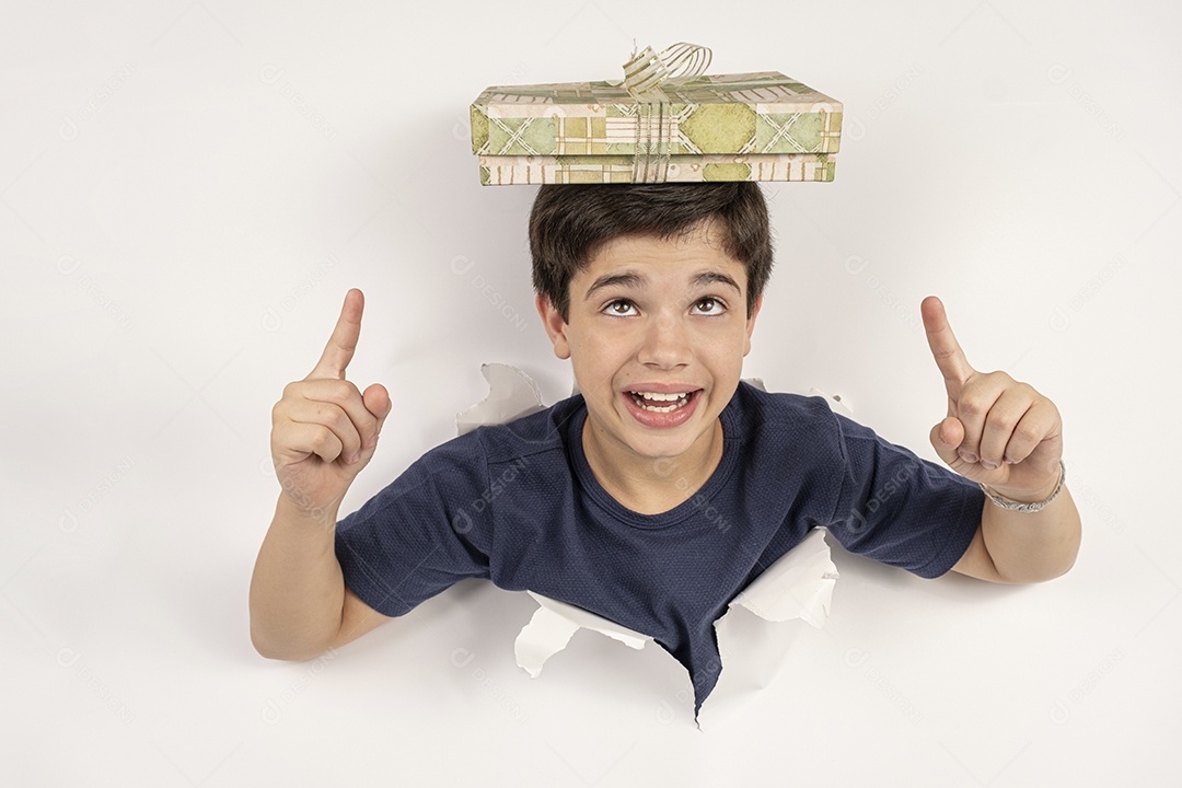 Criança brasileira com o corpo atravessado em uma cartolina branca e o presente na cabeça