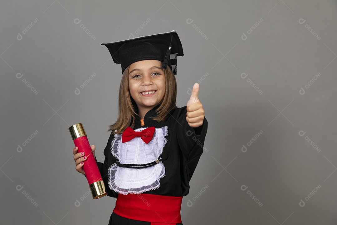 Feliz menina usando beca em formatura infantil