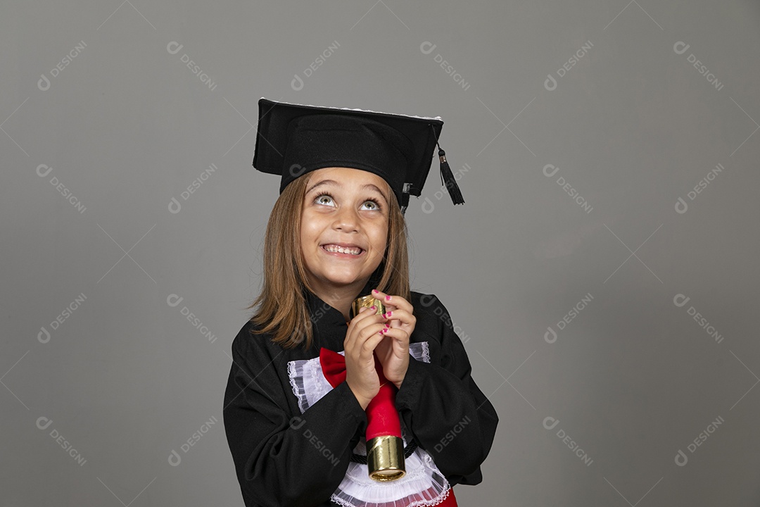 Linda garotinha com beca de formatura olhando para cima