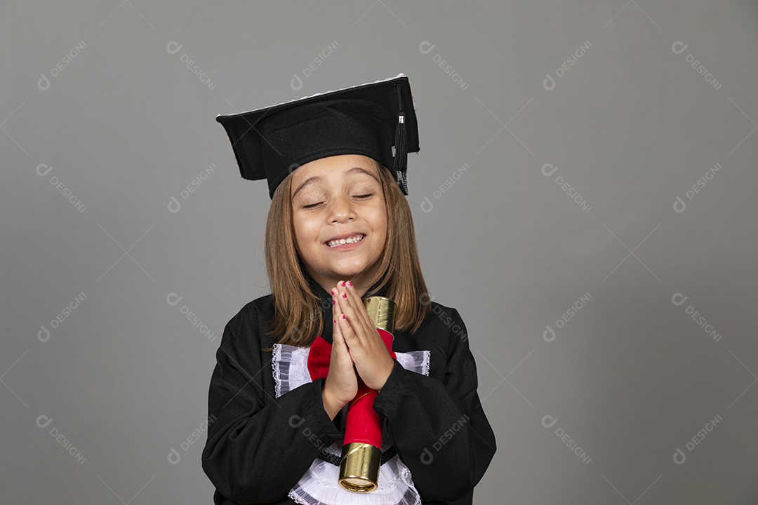 Linda menina com mãos agradecendo e usando beca