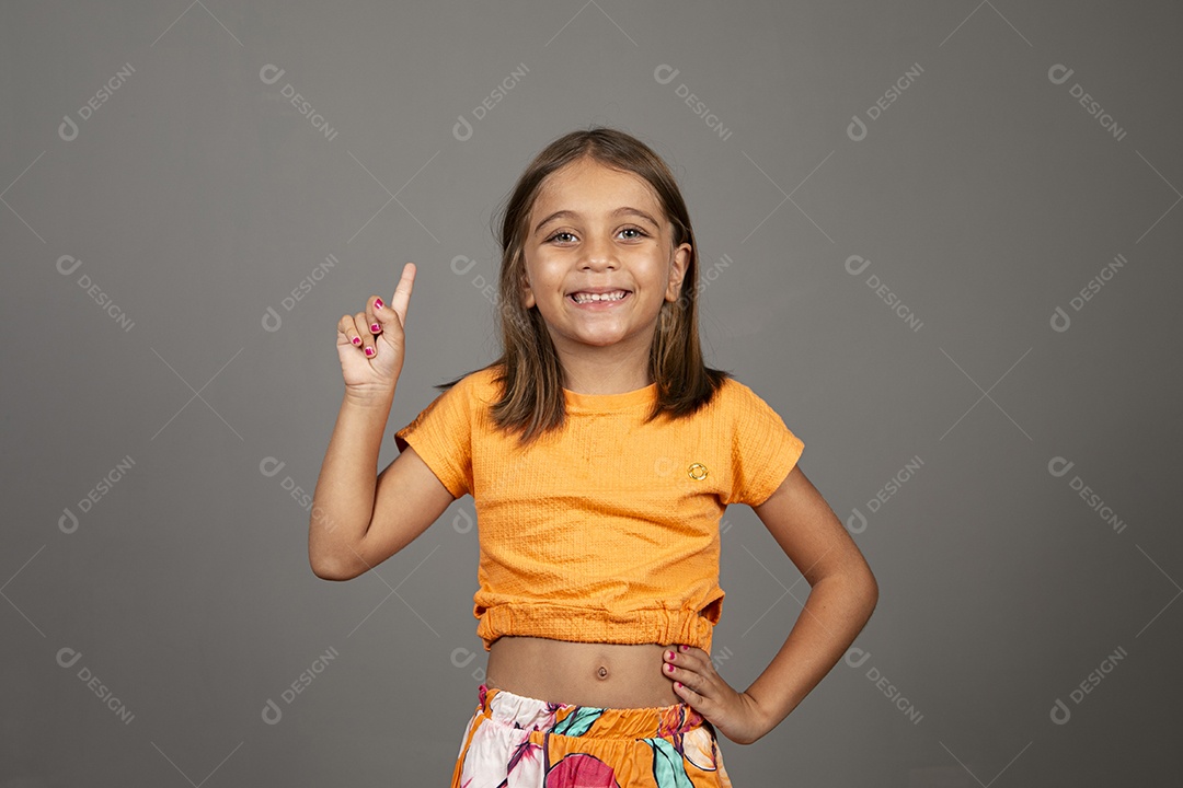 Linda menina usando roupa amarela apontando para cima