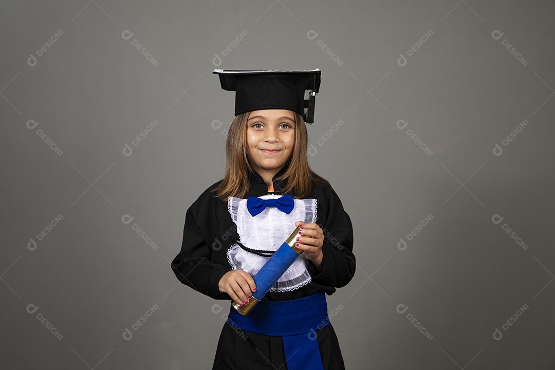 Adorável garotinha com beca e canudo de diploma nas mãos