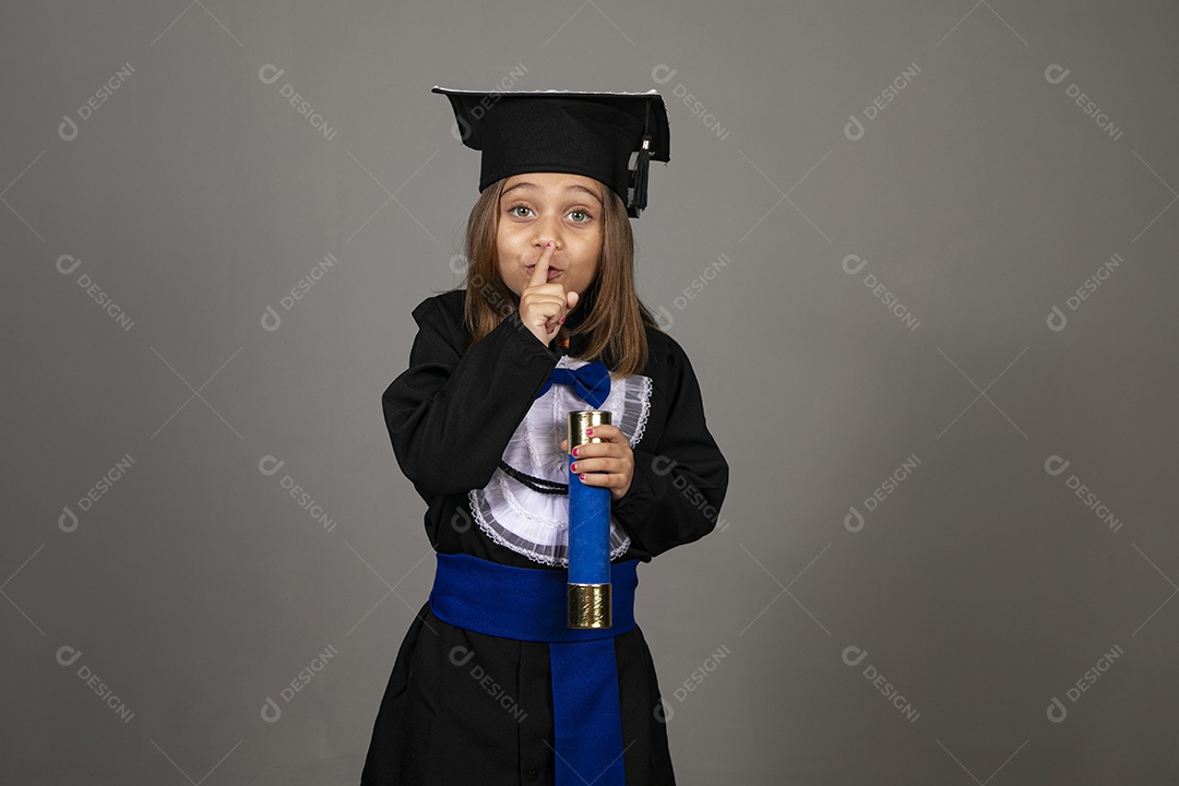 Menina feliz com roupa de formatura fazendo gesto de silêncio