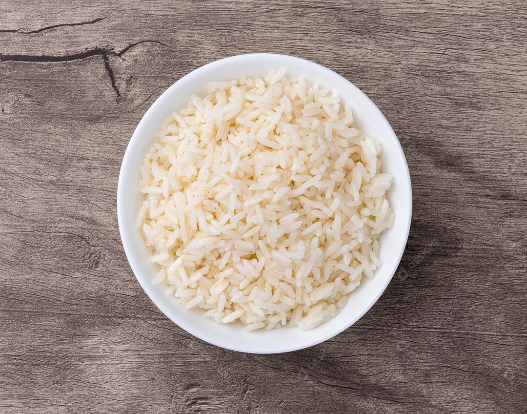 Arroz branco cozido em uma tigela sobre a mesa de madeira
