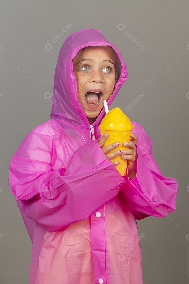 Linda menina usando capa rosa sobre fundo isolado segurando garrafa