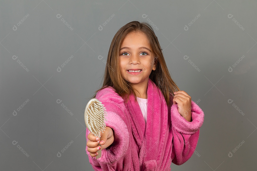 Linda menina usando roupão de banho segurando escova de cabelo sobre fundo isolado