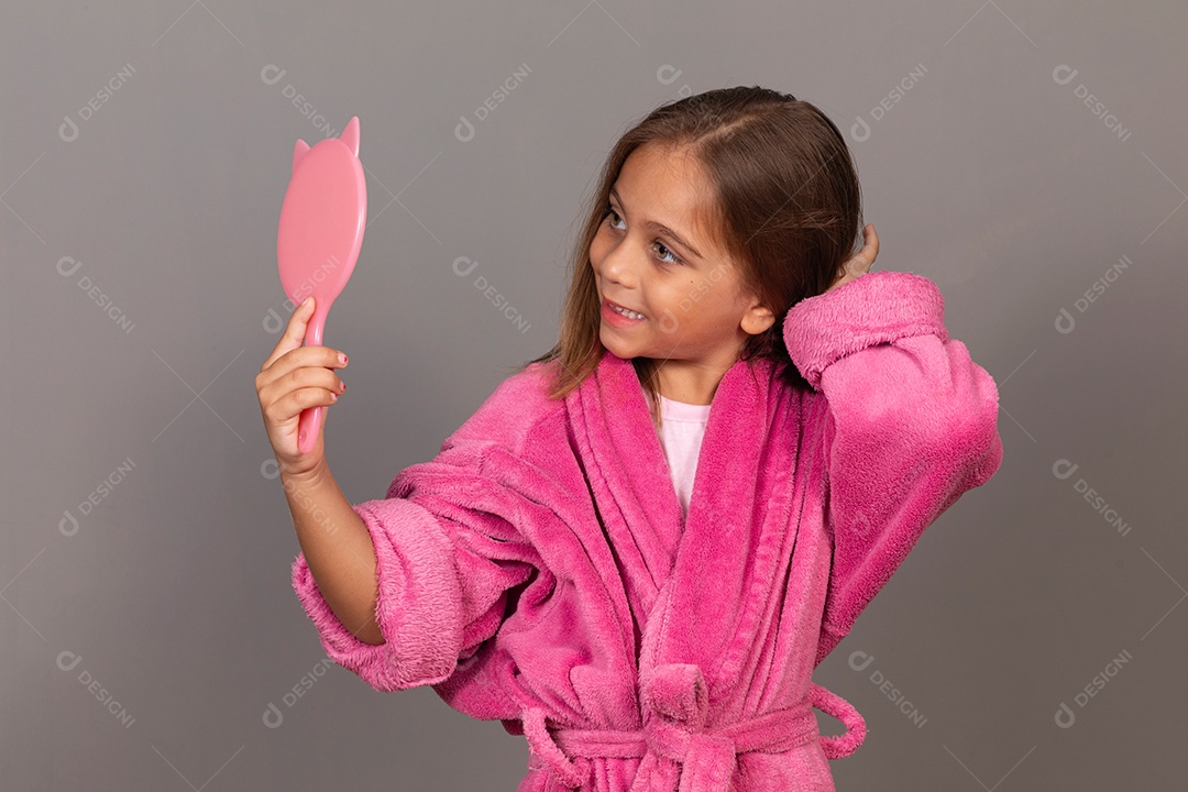 Linda menina usando roupão de banho rosa sobre fundo isolado segurando espelho
